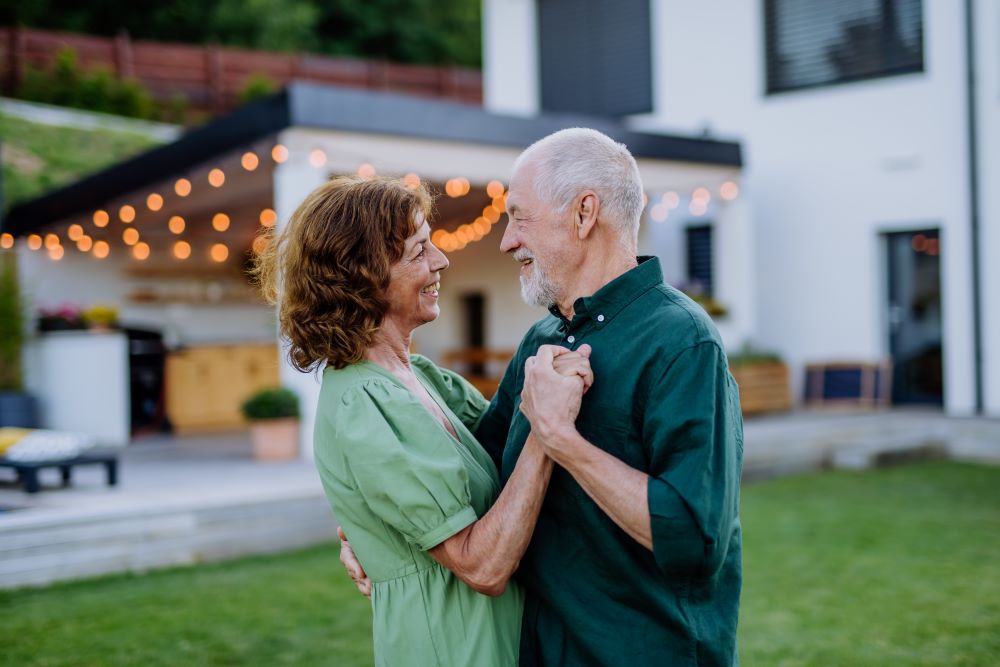 Senior couple in front of their house hugging